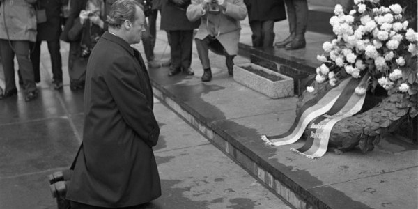 Zdjęcie archiwalne biało-czarne z 1970 roku, na którym kanclerz RFN Willy Brandt wykonuje symboliczny gest - klęka przed pomnikiem Bohaterów Getta w Warszawie, oddając hołd ofiarom Zagłady. F